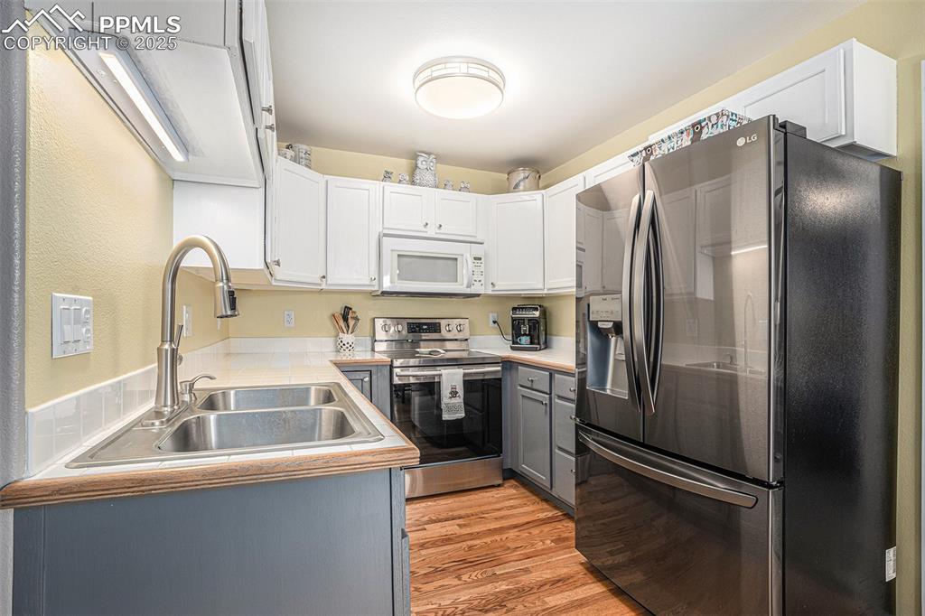 Image 8 of 22: Bright kitchen with two tone cabinets, stainless steel appliances, and hard
