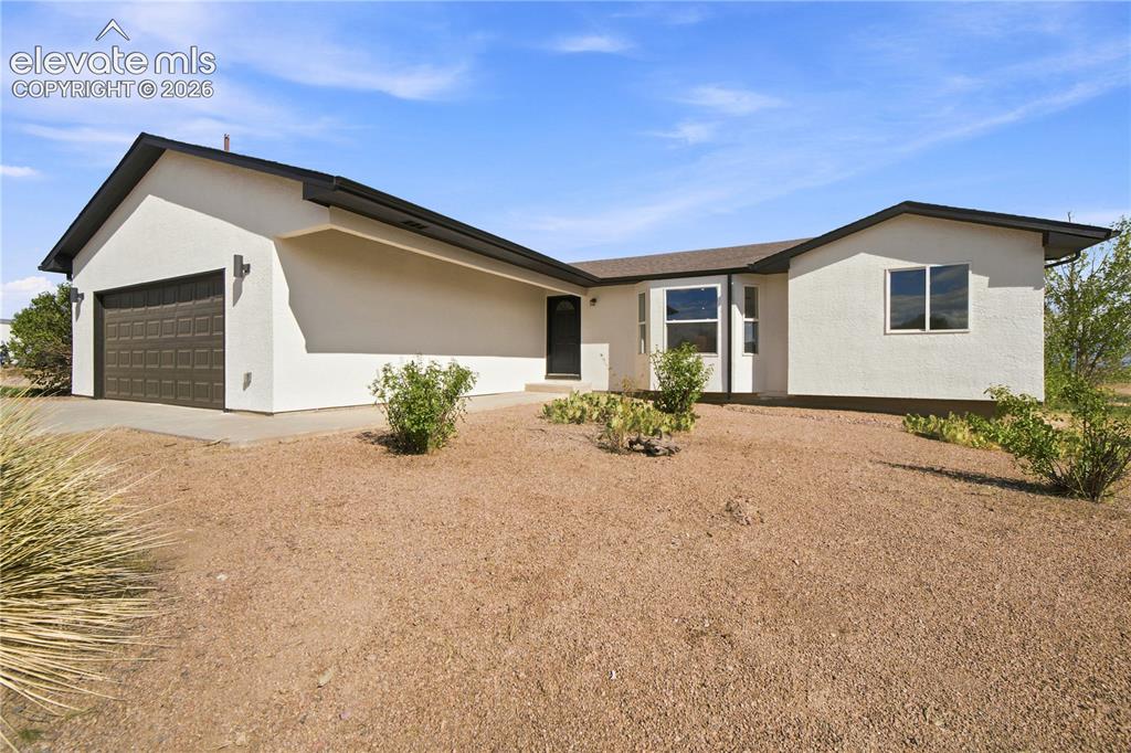 Image 1 of 40: Contemporary stucco exterior with a dark brown paneled garage door, a cover
