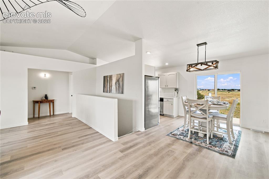 Image 12 of 40: Open-concept living area with light wood-finish flooring