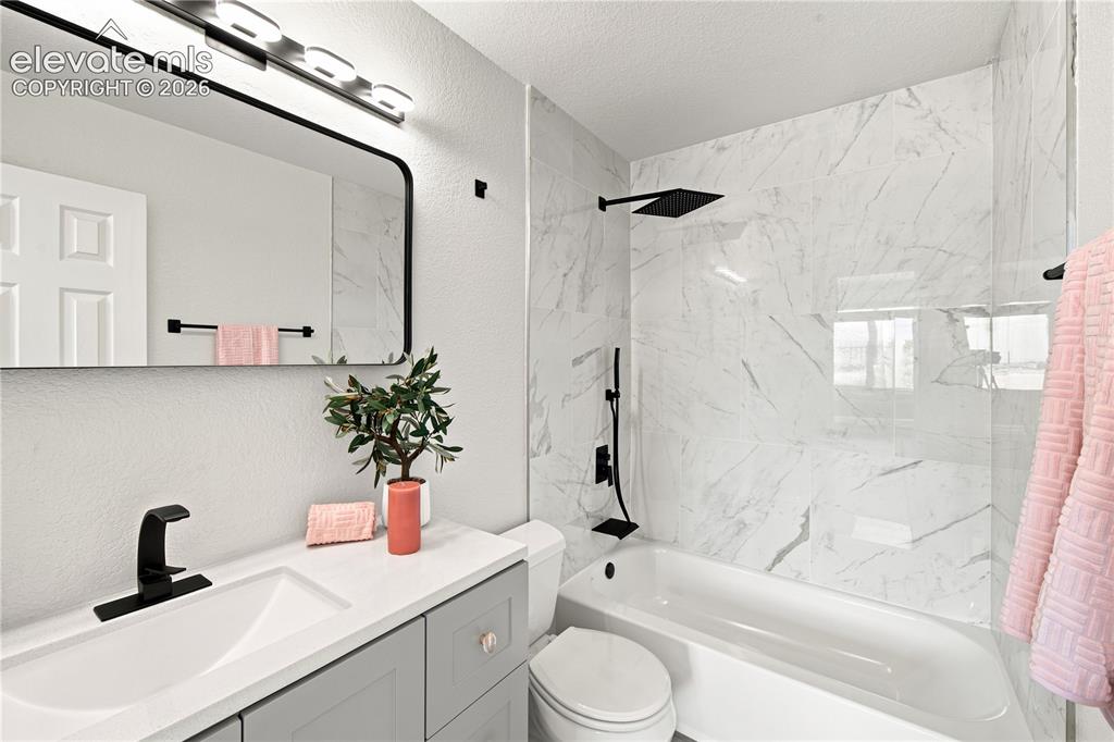 Image 15 of 40: Bathroom featuring a single vanity with stone-finish countertop, gray cabin