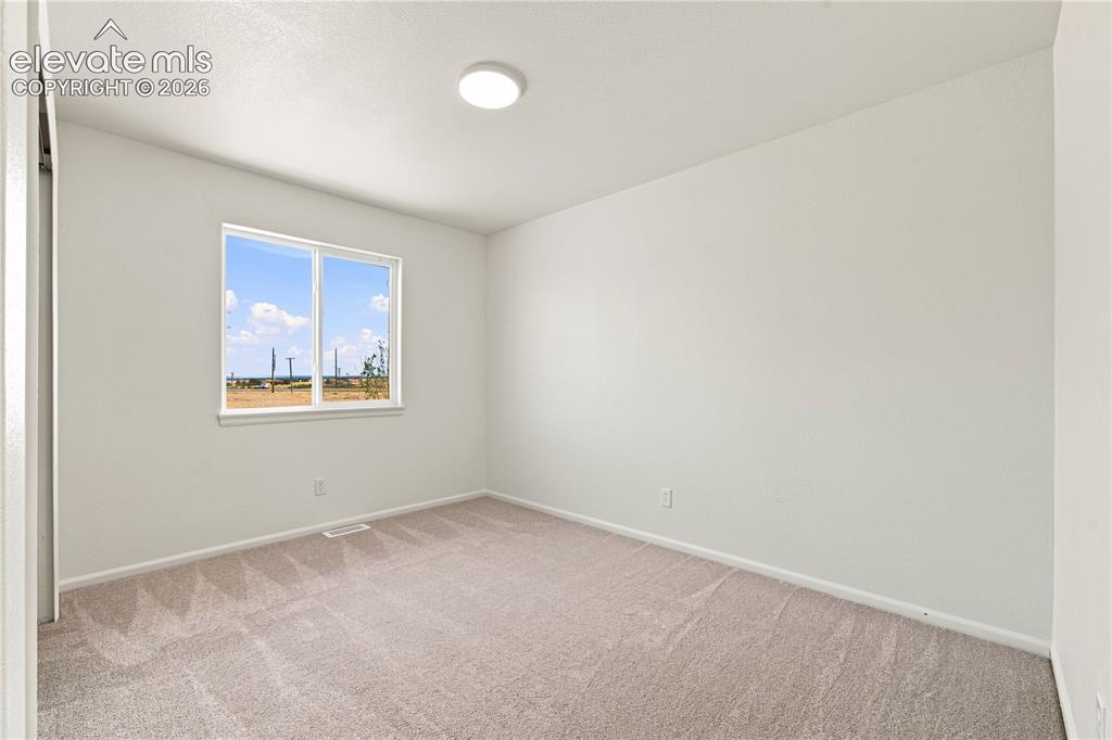 Image 21 of 40: Bright room featuring a double-pane window, neutral carpet, white walls, an