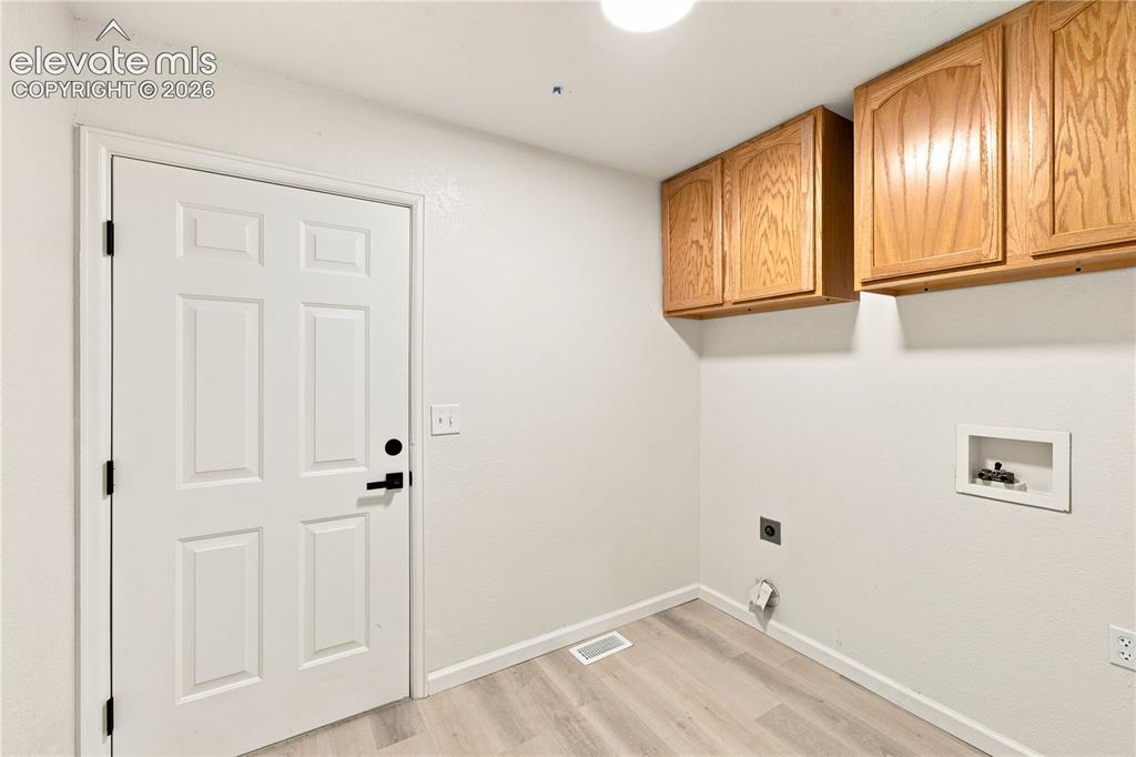 Image 26 of 40: Utility room featuring wood-finish cabinetry, light wood-finish flooring, a