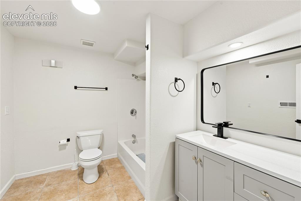 Image 30 of 40: Contemporary bathroom featuring a light gray vanity with a white countertop