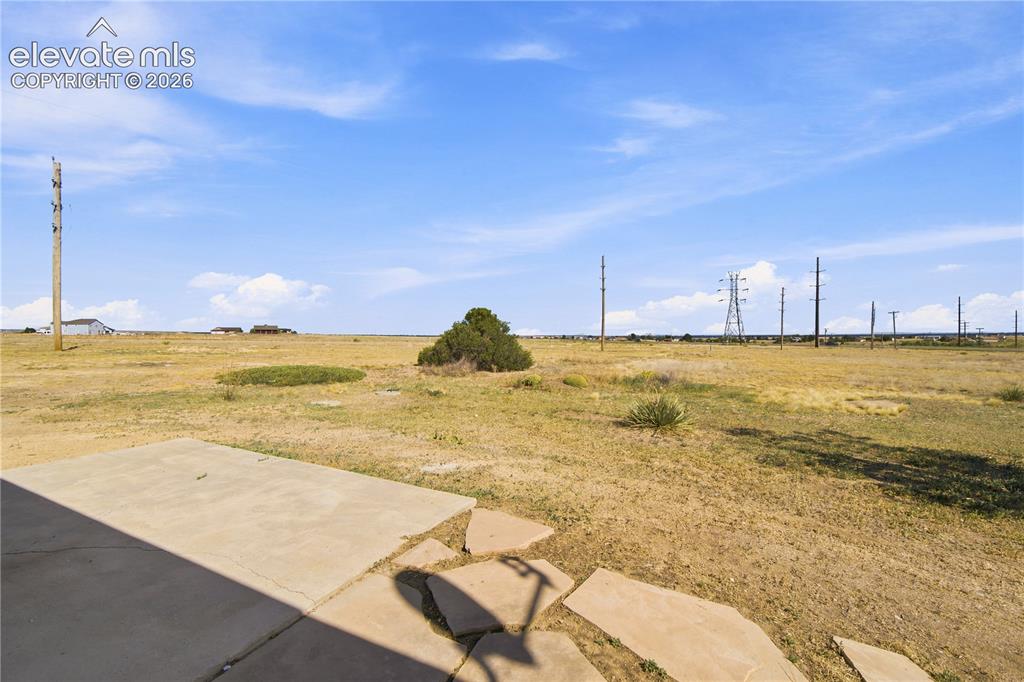 Image 34 of 40: Expansive open land featuring a concrete patio, natural vegetation, and a c