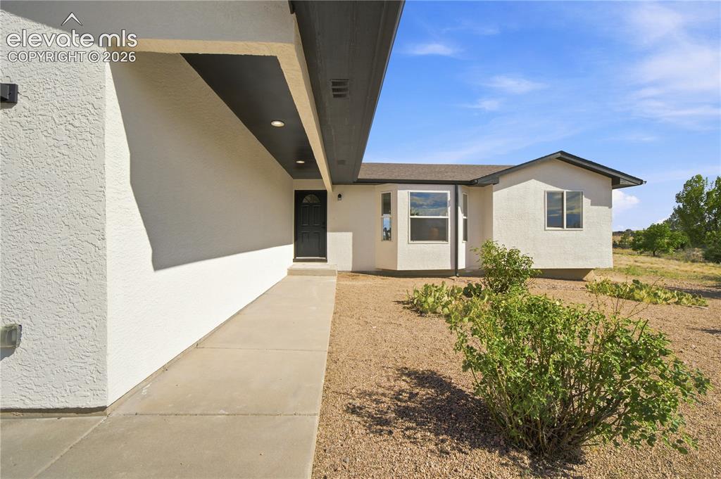 Image 36 of 40: Contemporary stucco exterior with a covered entry, recessed lighting, and a