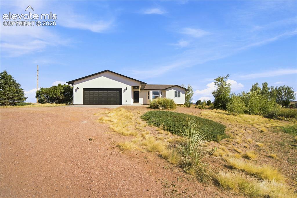 Image 37 of 40: Contemporary stucco exterior with an attached two-car garage, black front d