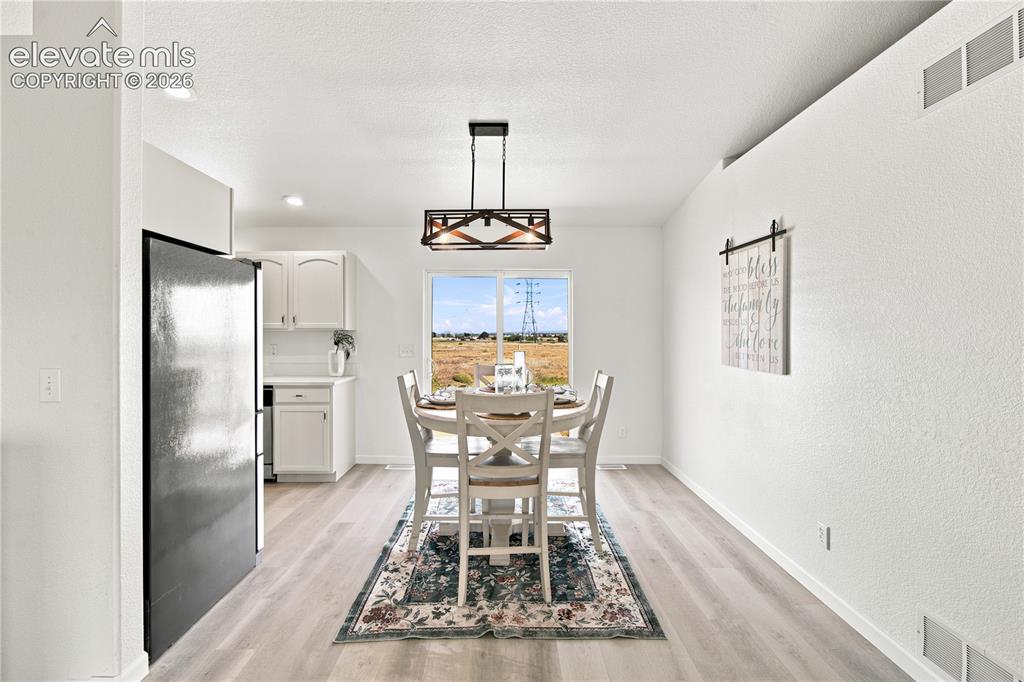 Image 8 of 40: Dining area featuring wood-finish flooring, a contemporary chandelier, and 