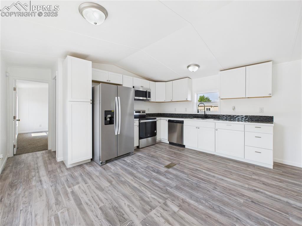 Image 11 of 49: Kitchen – Modern kitchen with crisp white cabinetry, stainless steel applia