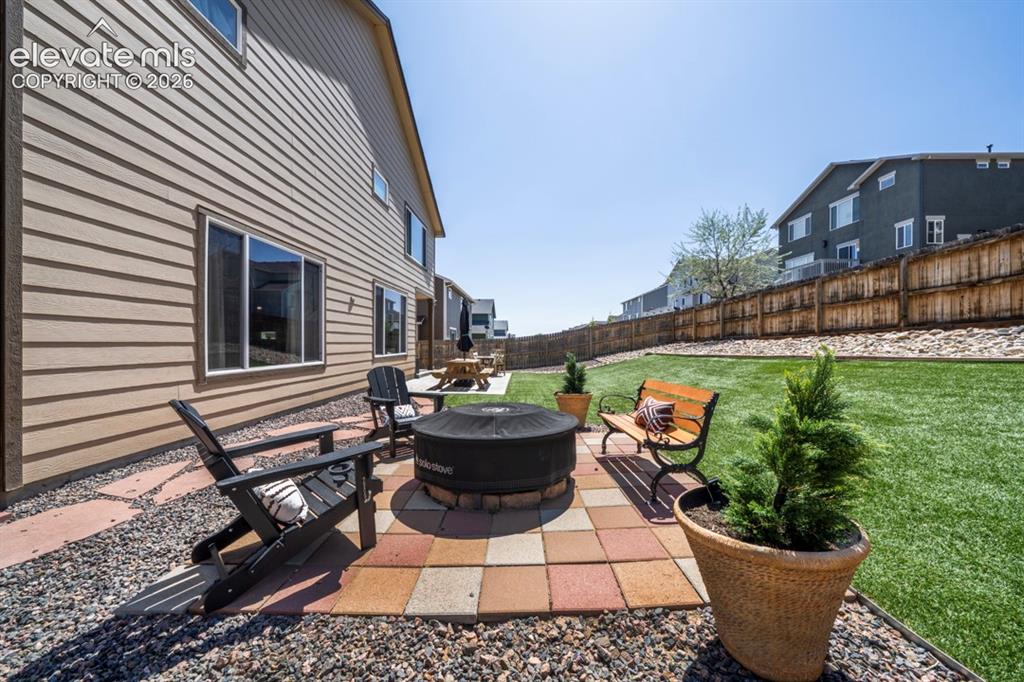 Image 42 of 50: Backyard, astroturf, covered patio, firepit, flagstone walkway, storage she