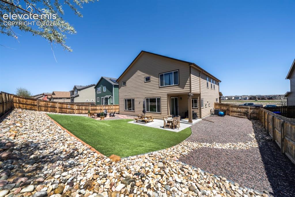 Image 43 of 50: Backyard, astroturf, covered patio, firepit, flagstone walkway, storage she