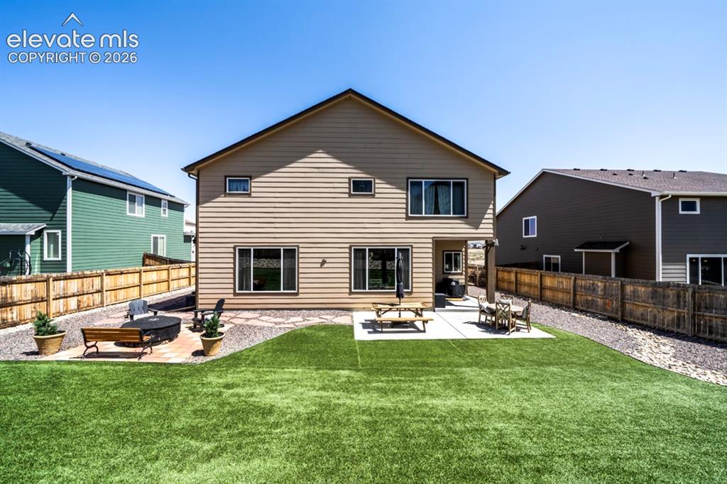 Image 44 of 50: Backyard, astroturf, covered patio, firepit, flagstone walkway, storage she