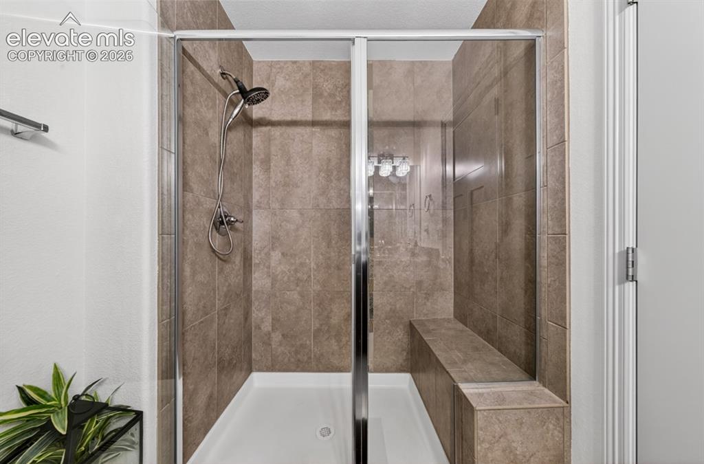 Image 9 of 50: Main level, granite, tile shower w/ built-in bench