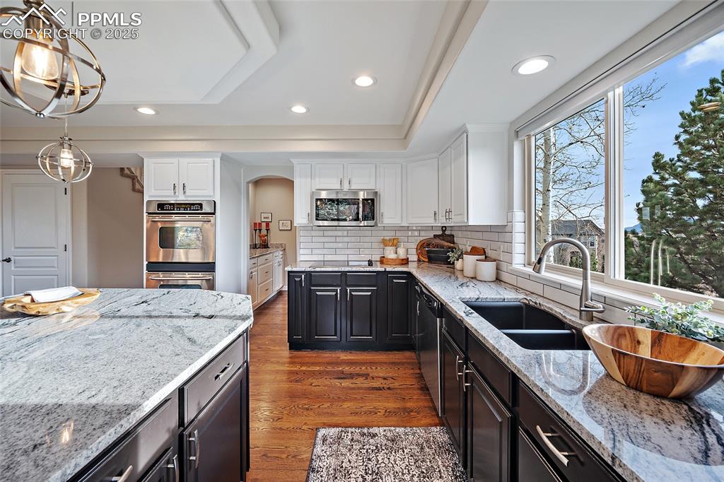 Image 10 of 50: Kitchen featuring granite counters, dark natural wood floors, double ovens,