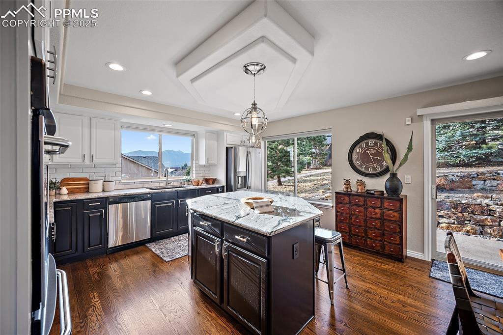Image 11 of 50: Kitchen featuring granite countertops, tasteful backsplash, dark natural wo