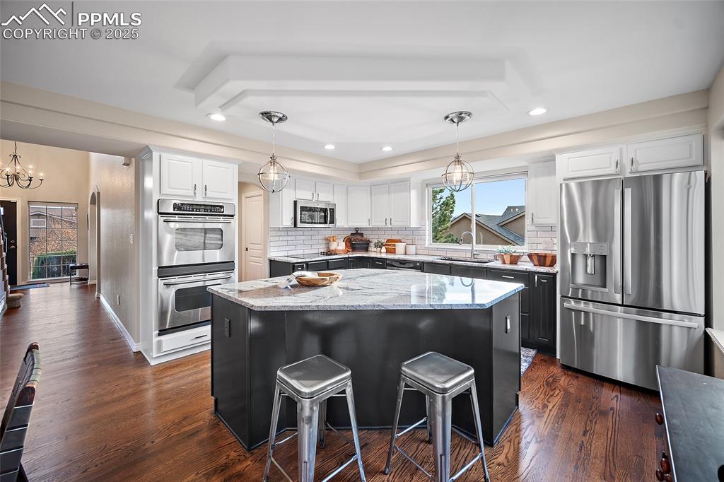 Image 13 of 50: Kitchen with stainless steel appliances, pendant lighting, a breakfast bar,