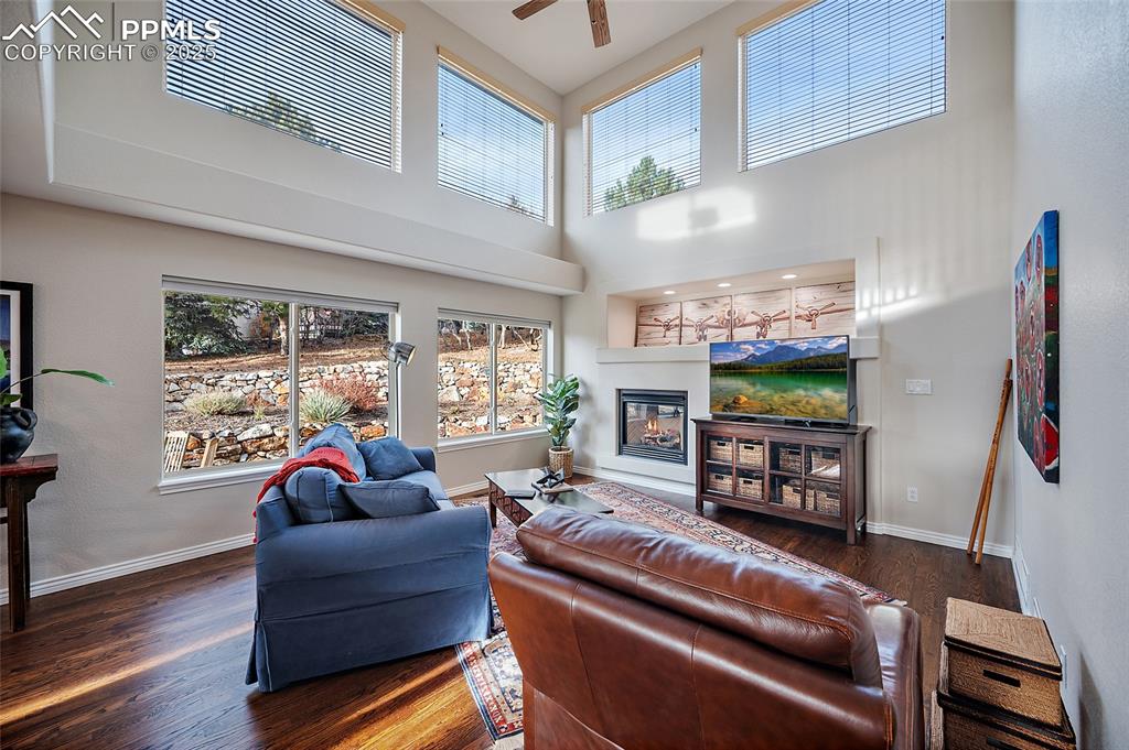 Image 16 of 50: Living area with a towering ceiling, tons of windows and gas fireplace.