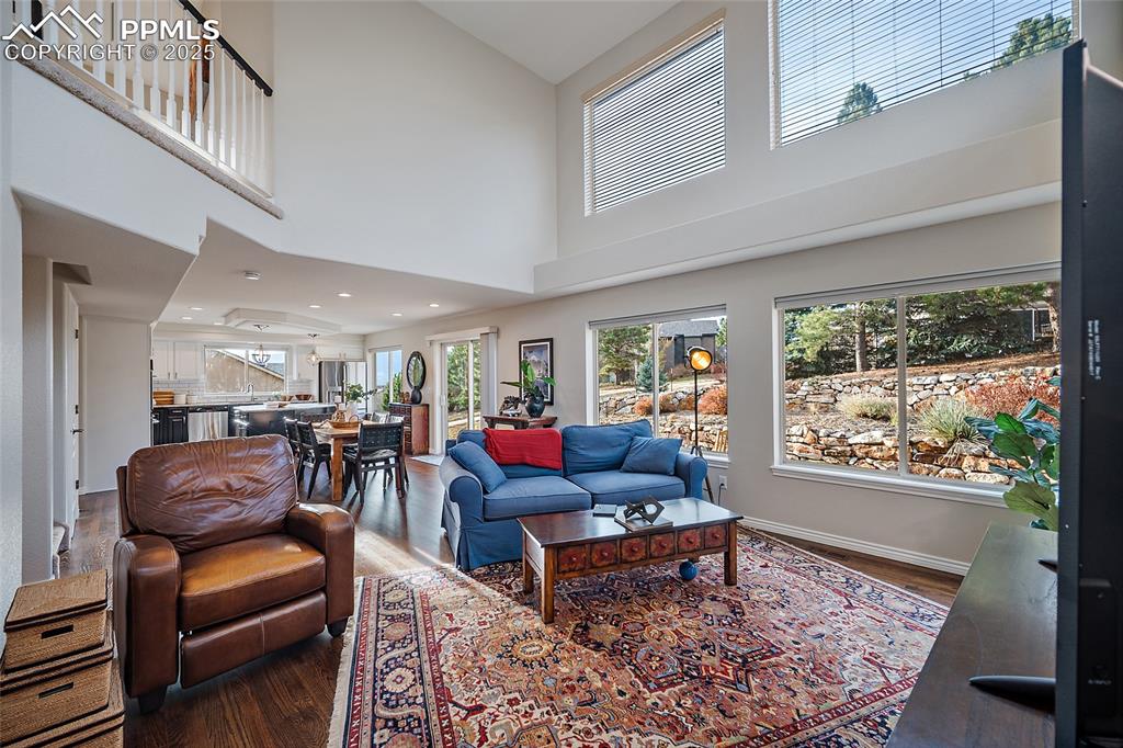 Image 18 of 50: Living room featuring dark natural wood floors, a towering ceiling, plenty 