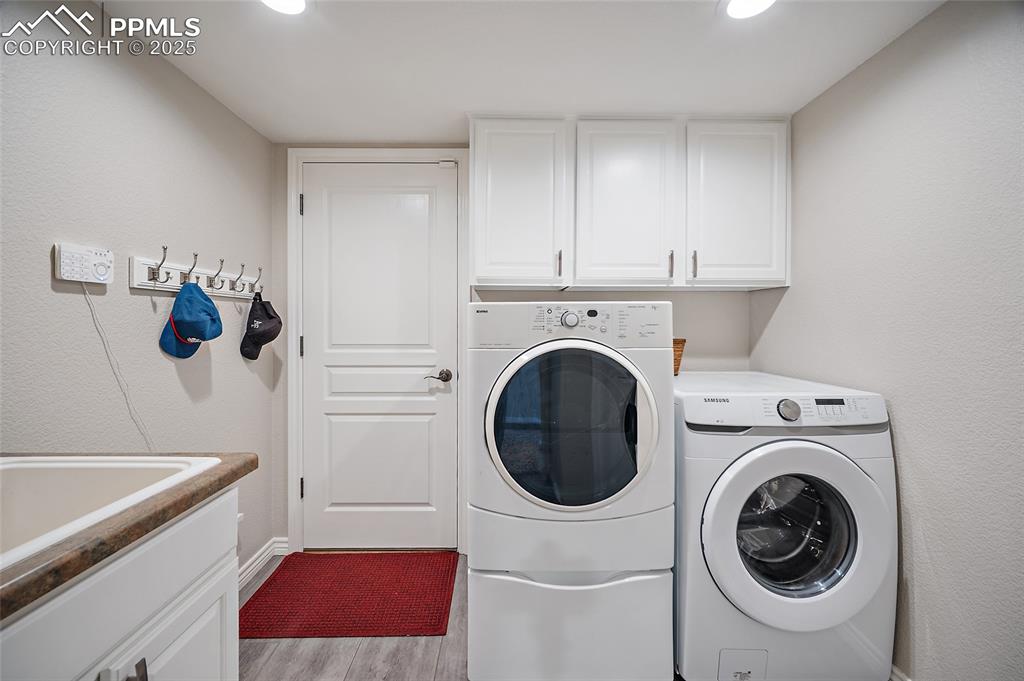 Image 20 of 50: Washroom featuring, cabinet space, washing machine and dryer, utility sink,