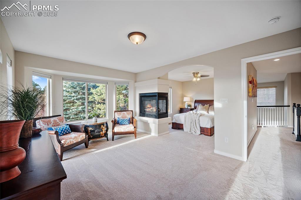 Image 26 of 50: Carpeted bedroom with baseboards and a multi sided fireplace
