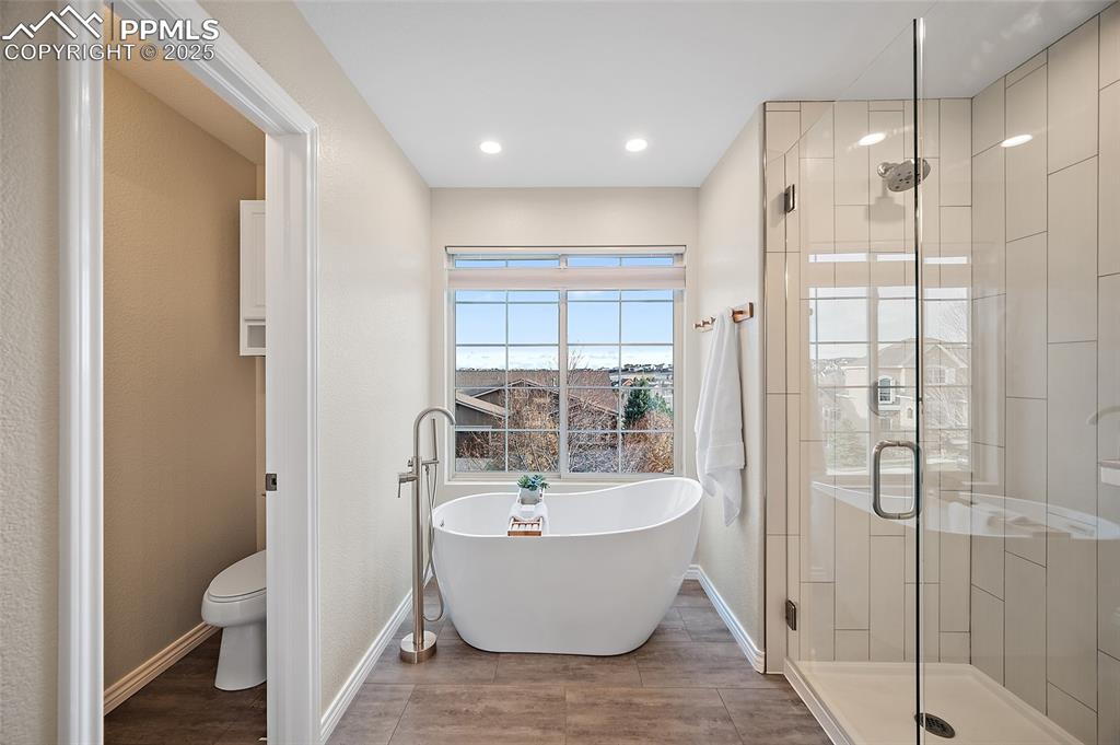 Image 30 of 50: Full bathroom featuring a soaking tub, a shower stall, luxury vinyl tile fl