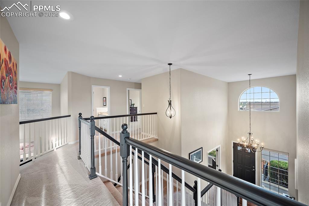 Image 34 of 50: Upper level hallway featuring healthy amount of natural light, a chandelier