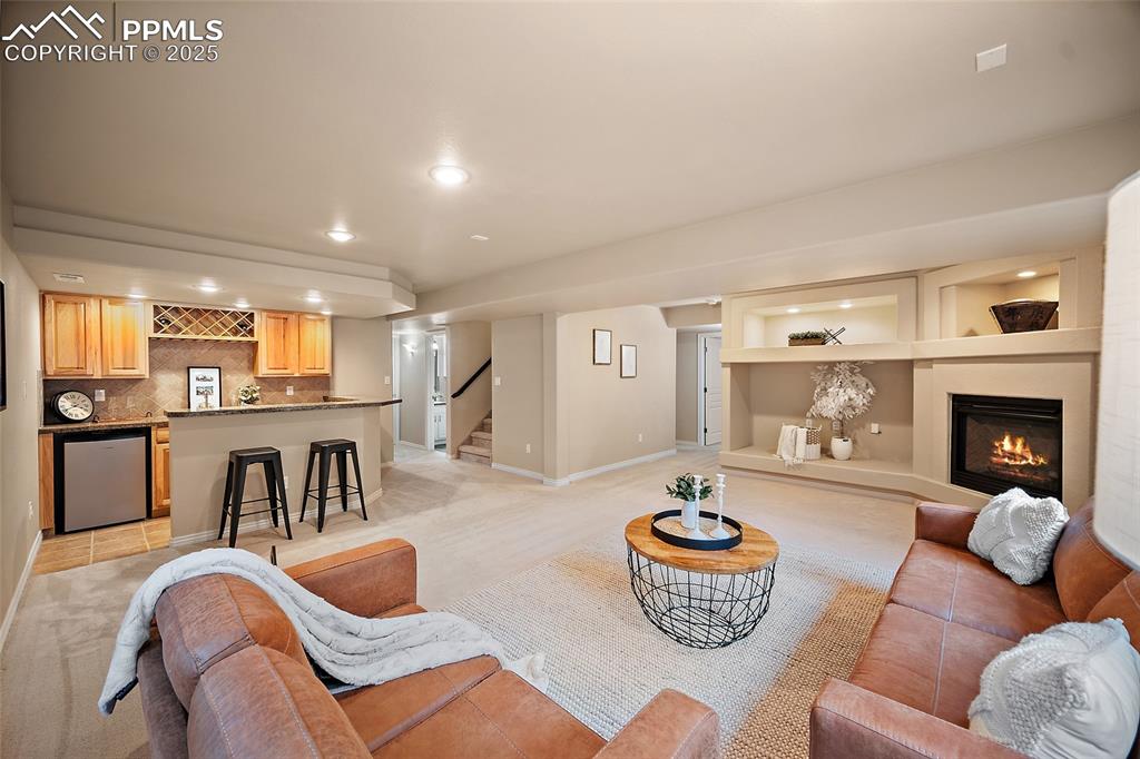 Image 35 of 50: Lower level family room featuring wet bar, fireplace, and newer carpet.