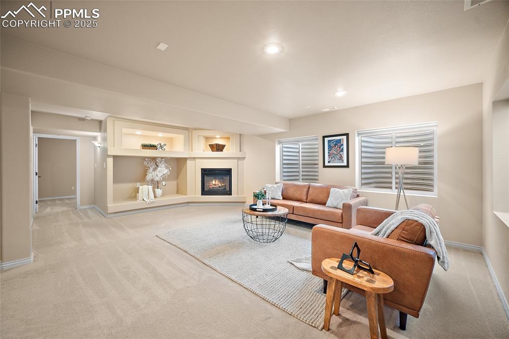 Image 36 of 50: Lower level family room with a fireplace and recessed lighting.