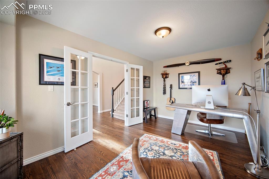 Image 6 of 50: Office area with french doors and wood finished floors.