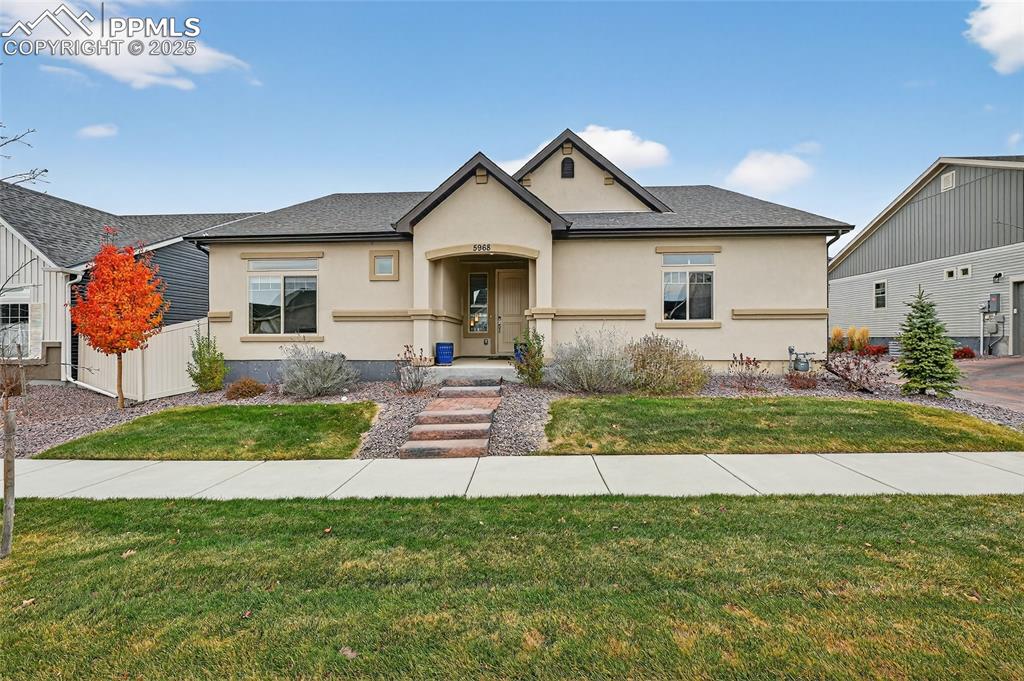 Caption: View of front of house with a front yard, stucco siding, and a shingled roof
