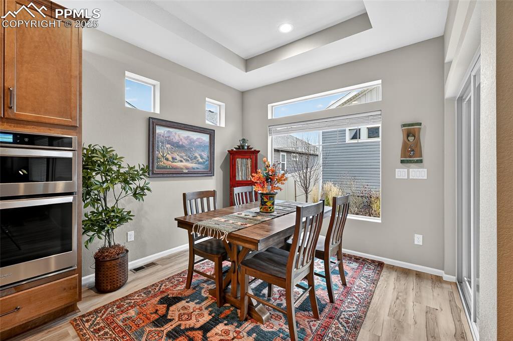 Image 17 of 43: Dining area featuring light wood-style flooring, a tray ceiling, and health