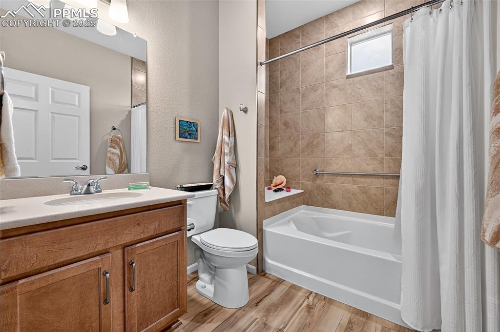 Image 8 of 43: Full bath featuring vanity, a textured wall, shower / tub combo, and light