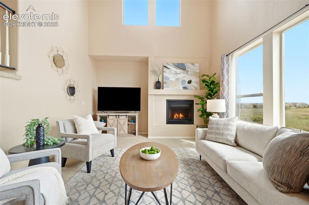 Image 10 of 40: Open living room with high ceilings, tons of natural light, and a gas firep