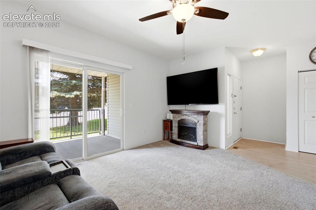 Image 12 of 25: Carpeted living area with a ceiling fan, sliding glass door to a balcony, a