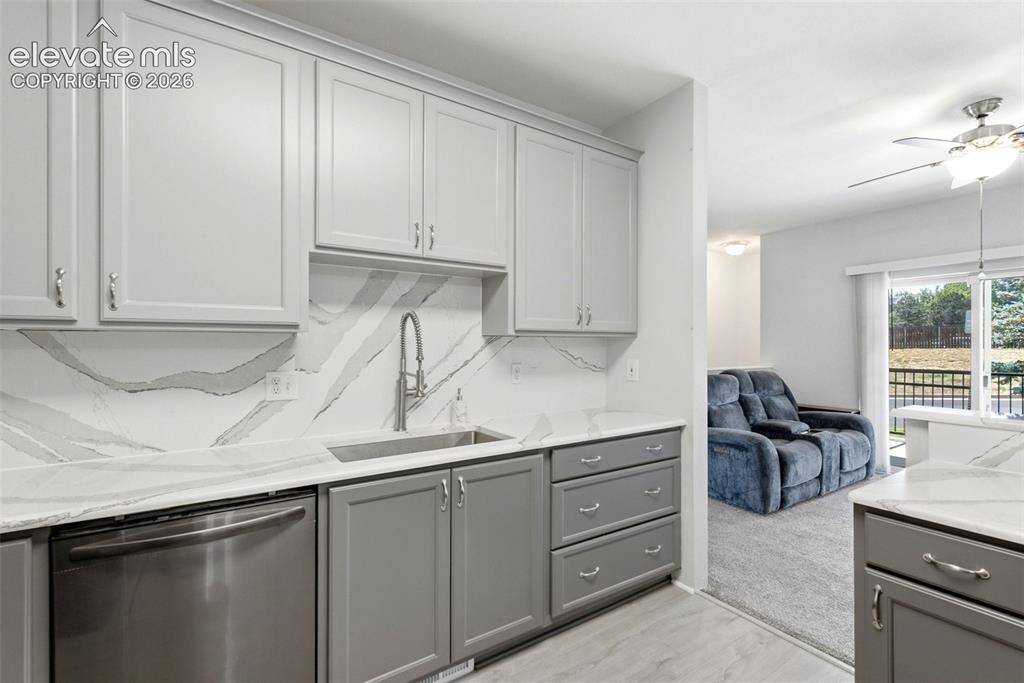 Image 13 of 25: Modern kitchen with light gray cabinetry, stainless steel dishwasher, under