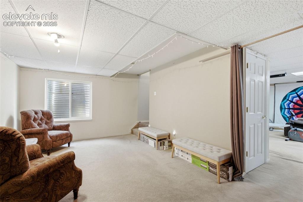 Image 17 of 25: Carpeted living area with a single window, recessed lighting, and a drop ce