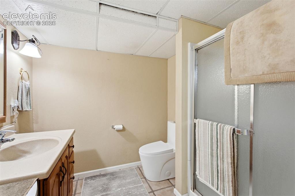 Image 20 of 25: Bathroom featuring a vanity with wood-finish cabinetry, shower enclosure wi