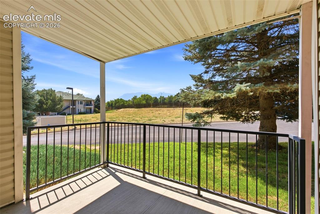 Image 21 of 25: Covered balcony with a concrete floor and black metal railing