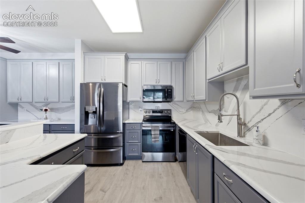 Image 7 of 25: Kitchen featuring two-tone cabinetry, expansive white countertops with vein