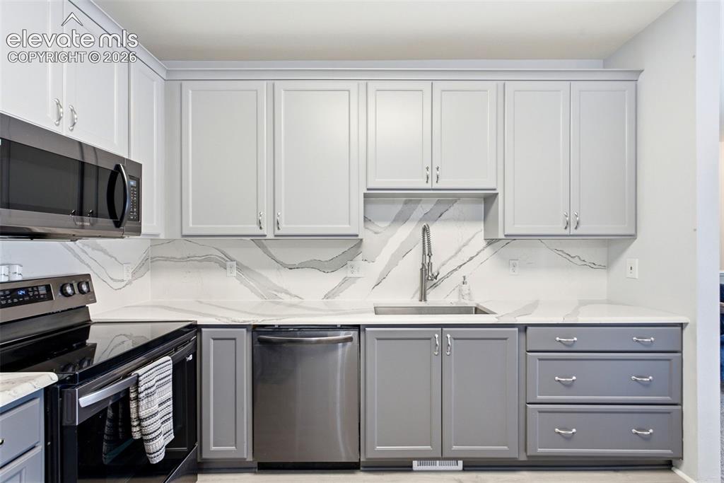 Image 8 of 25: Modern kitchen featuring white shaker-style cabinetry with brushed nickel h