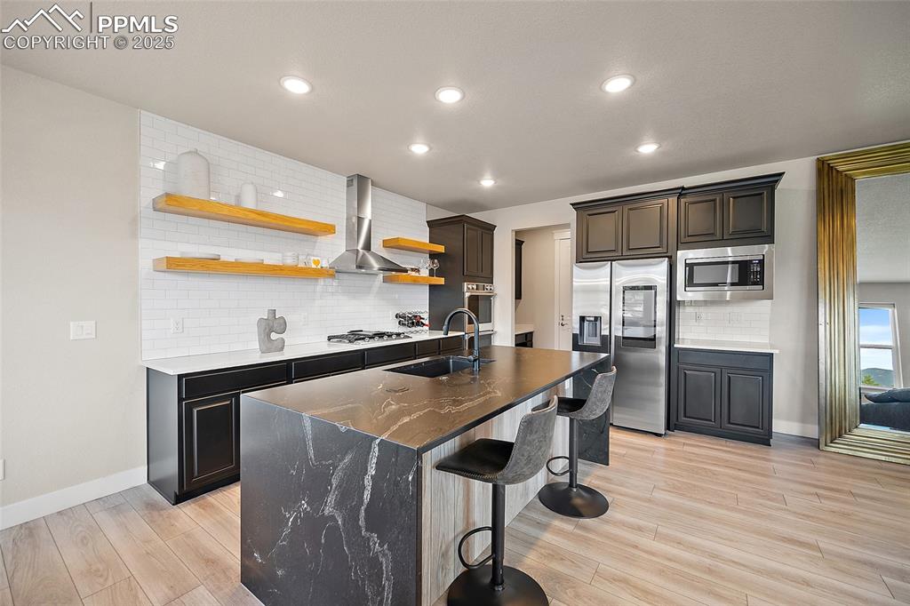 Image 17 of 46: Kitchen with decorative backsplash, open shelves, a breakfast bar, stainles