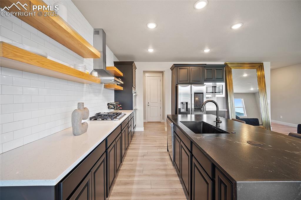 Image 18 of 46: Kitchen with recessed lighting, a center island with sink, open shelves, st