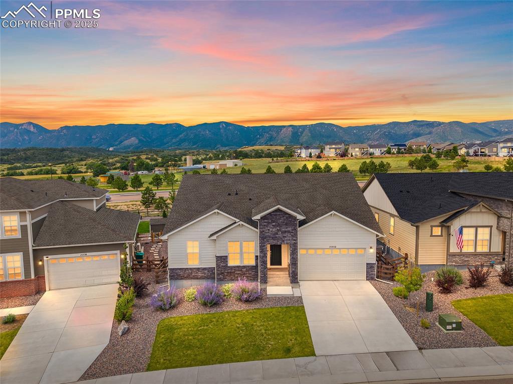 Image 2 of 46: View of front of home with stone siding, a mountain view, driveway, and an