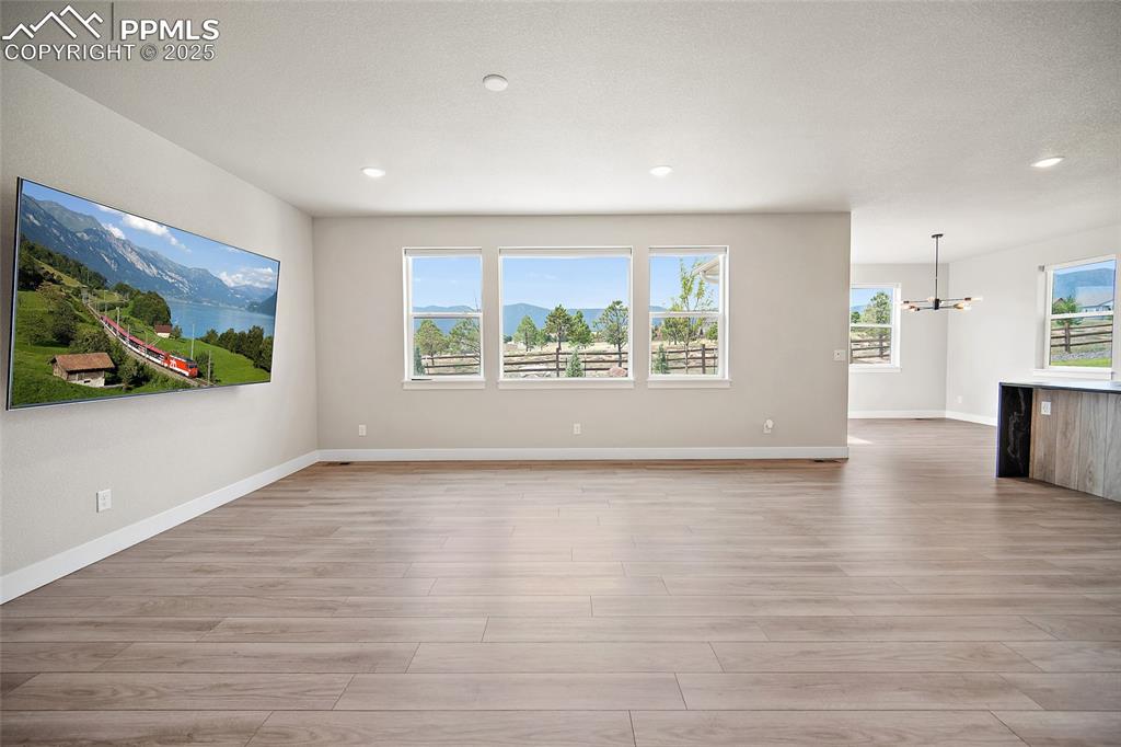 Image 20 of 46: Unfurnished living room with light wood finished floors, a chandelier, and