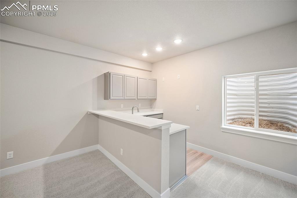 Image 39 of 46: Kitchen with gray cabinetry, light colored carpet, a peninsula, and recesse