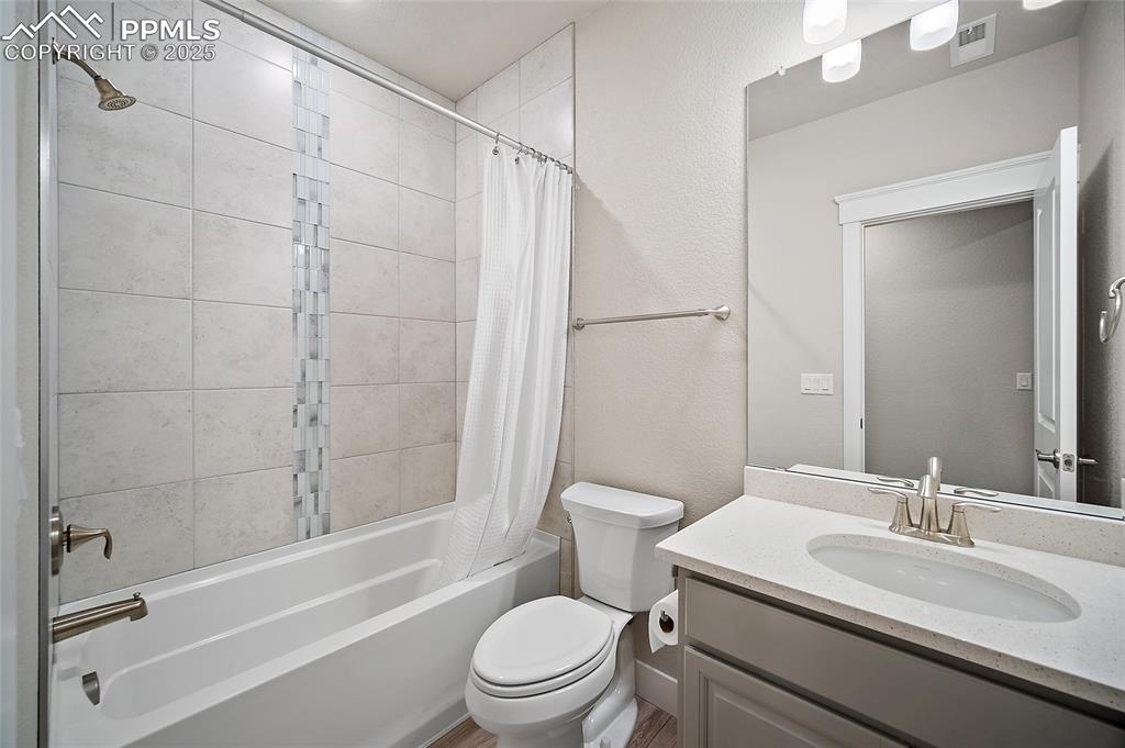 Image 40 of 46: Bathroom with shower / tub combo, vanity, and a textured wall