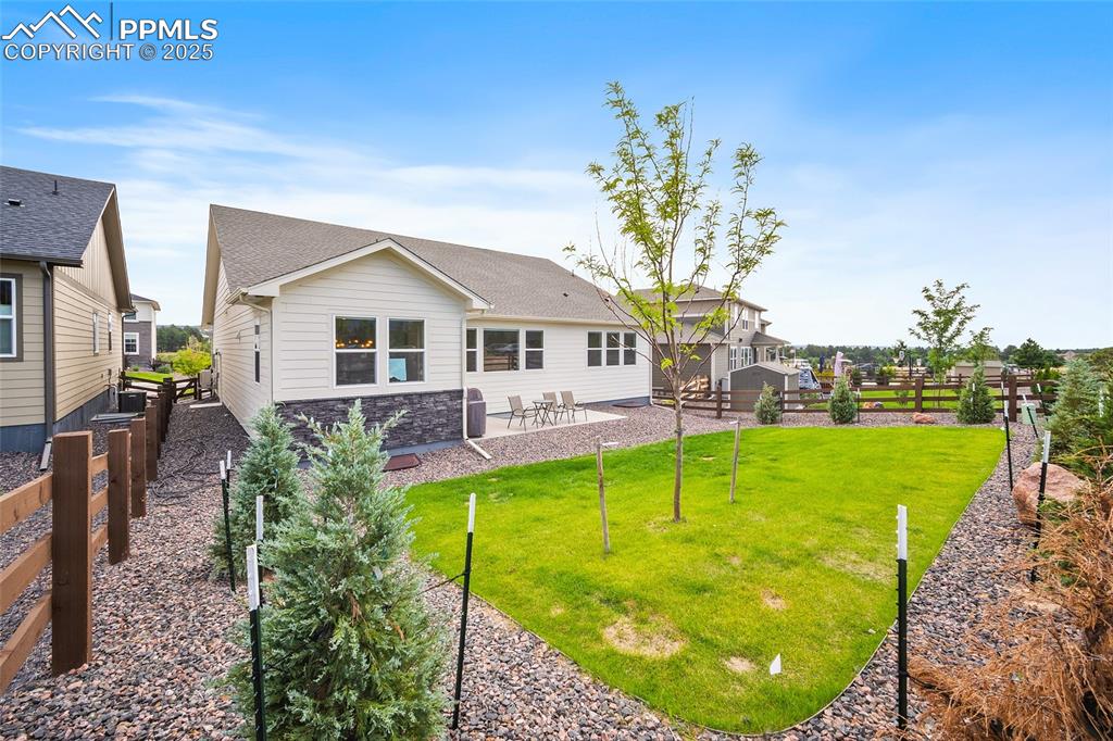 Image 45 of 46: Back of property with a fenced backyard, a patio, stone siding, and a shing