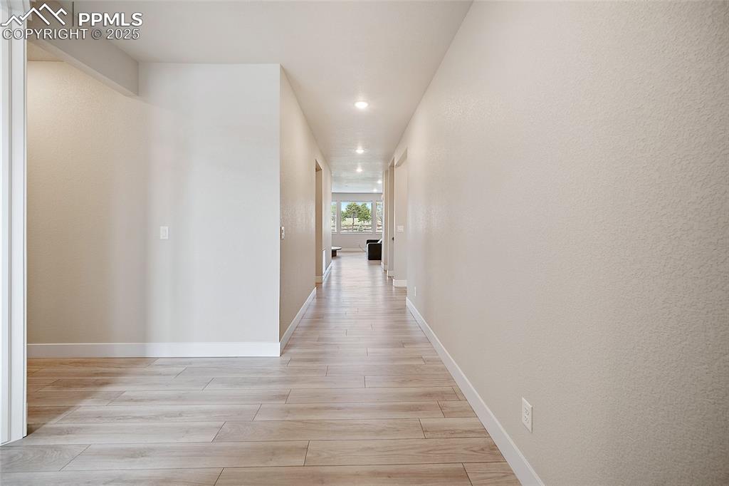 Image 6 of 46: Corridor featuring light wood finished floors, recessed lighting, and a tex