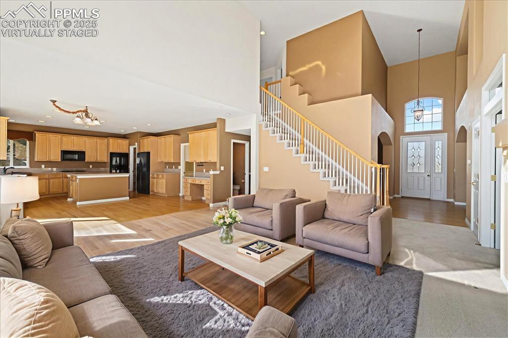 Image 10 of 33: Living room with a chandelier, a towering ceiling, light wood-style floorin