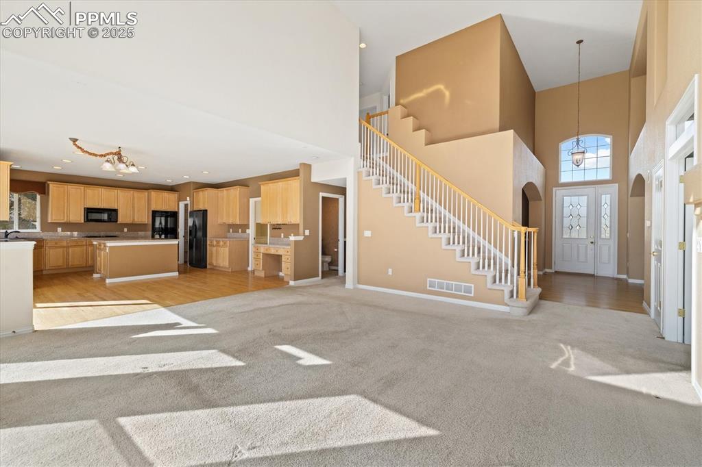 Image 11 of 33: Foyer featuring a chandelier, a towering ceiling, light colored carpet, arc