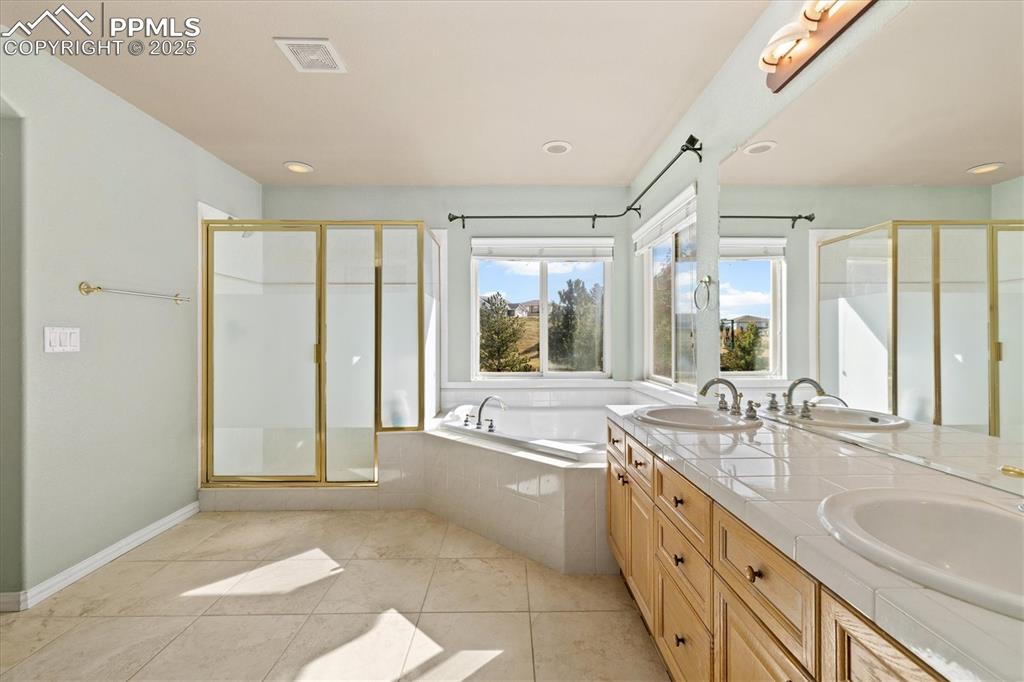 Image 17 of 33: Full bathroom with a bath, a shower stall, double vanity, light tile patter